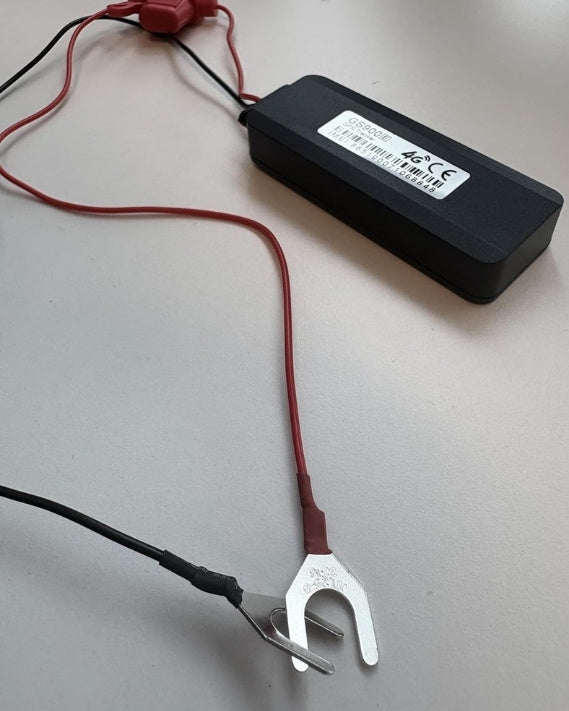 Close-up of the GS900 4G hardwired GPS tracker showing red and black power leads with battery terminal connectors for vehicle installation.